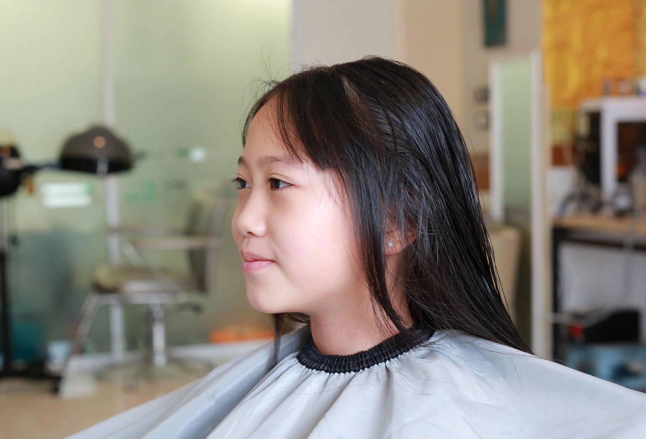 Preteen girl smiling during her haircut, emphasizing family-friendly service.